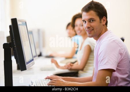Three people sitting in computer room typing and smiling Stock Photo