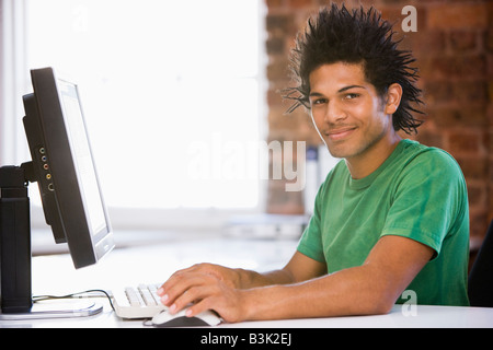 Businessman in office using computer and smiling Stock Photo