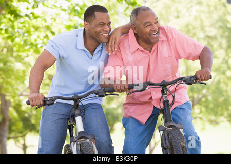 Two men on bikes outdoors smiling Stock Photo