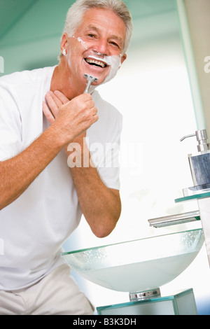 Man in bathroom shaving and smiling Stock Photo