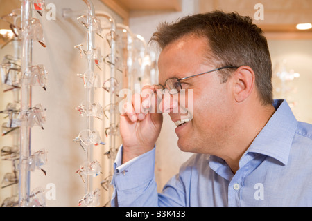 Man trying on eyeglasses at optometrists smiling Stock Photo