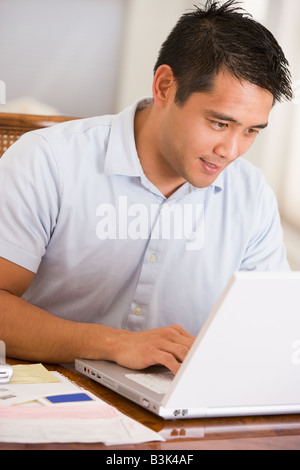 Man in dining room using laptop Stock Photo