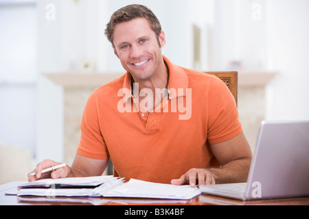 Man in dining room with laptop smiling Stock Photo