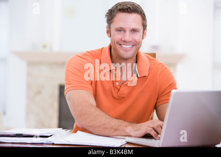 Man in dining room with laptop smiling Stock Photo
