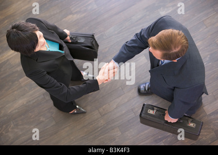 Two businesspeople indoors shaking hands Stock Photo