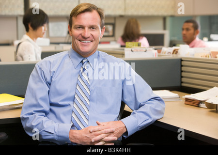 Businessman in cubicle smiling Stock Photo