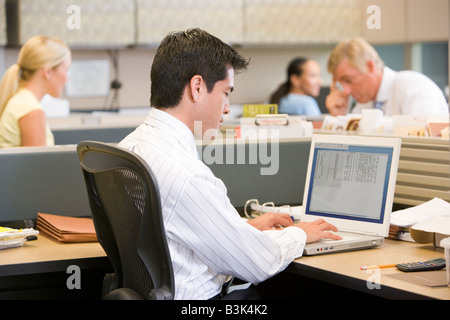 Businessman in cubicle using laptop Stock Photo