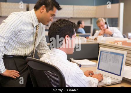 Two businessmen in cubicle looking at laptop Stock Photo