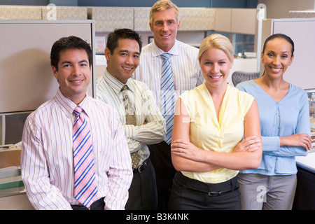 Business team standing in cubicle smiling Stock Photo