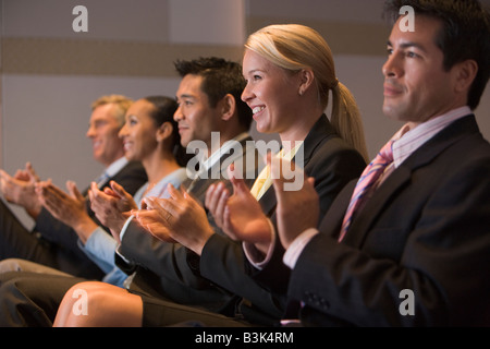 Five businesspeople applauding and smiling in presentation room Stock Photo