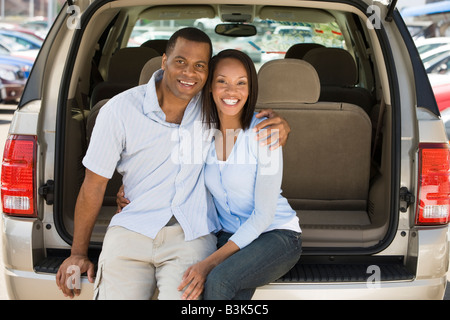 Couple sitting in back of van smiling Stock Photo