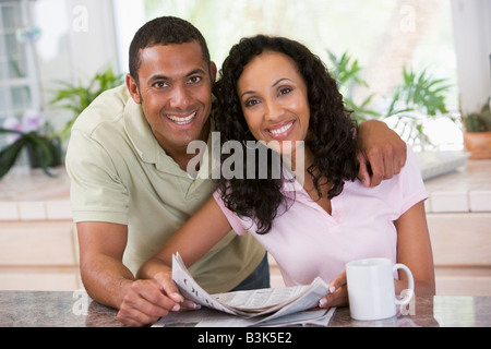 Couple in kitchen with newspaper and coffee smiling Stock Photo