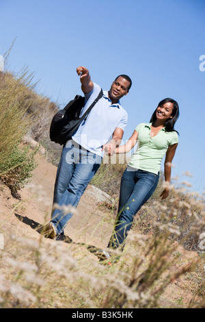 Couple walking on path holding hands and smiling Stock Photo
