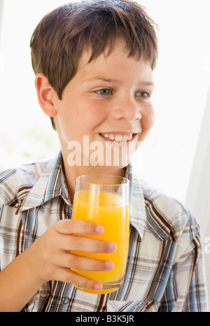 Young boy indoors drinking orange juice smiling Stock Photo