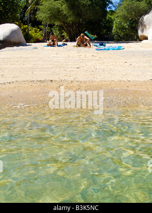 Two tourists relaxing on the beach with sea in foreground Chalok Baan Kao Koh Tao Thailand JPH0098