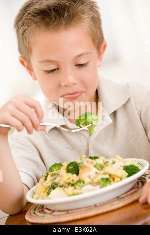 Young boy indoors eating pasta with brocolli Stock Photo