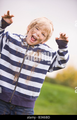 Young boy standing outdoors dirty and smiling Stock Photo