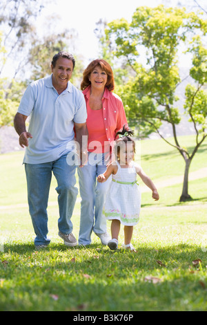 Grandparents walking in park with granddaughter Stock Photo