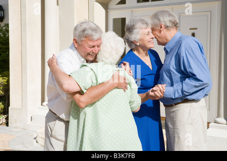 Two senior couples greeting each other with open arms Stock Photo