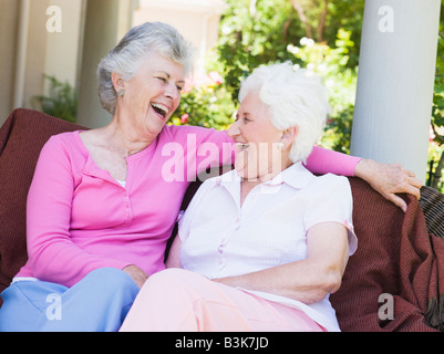Two senior women sitting outdoors on a chair Stock Photo