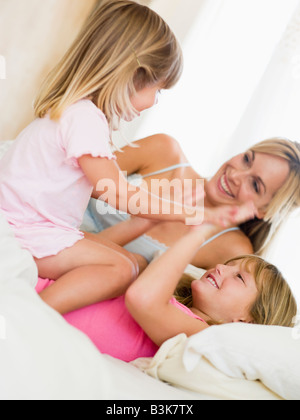 Woman and two young girls in bed playing and smiling Stock Photo