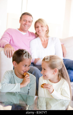 Family sitting in living room eating cookies and smiling Stock Photo