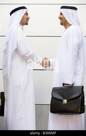 Two businessmen outdoors shaking hands and smiling Stock Photo