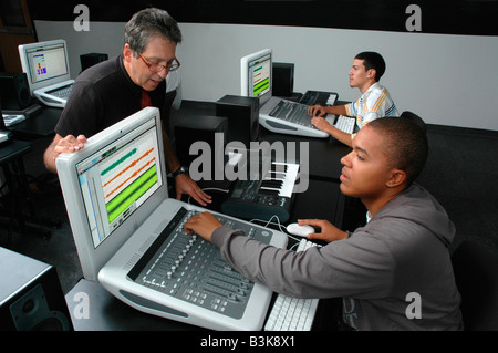 Students working with computerized audio mixing boards with an instructor supervising Stock Photo