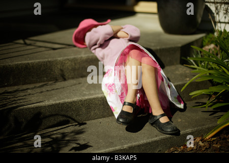 Five year old girl relaxes on steps in spring sunshine Stock Photo