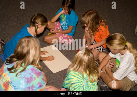 elementary age students work as a group on floor of classroom, brainstorming ideas together for science project, southwestern us Stock Photo