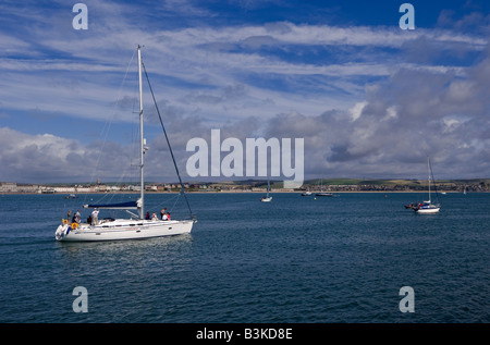 Yacht sails out to sea off the coast of Weymouth in Dorset Stock Photo