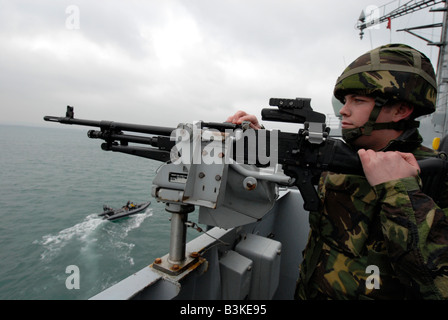 Armed guard on watch with a general purpose machine gun to hand Type 23 Duke Class Frigate 'HMS Portland' Stock Photo