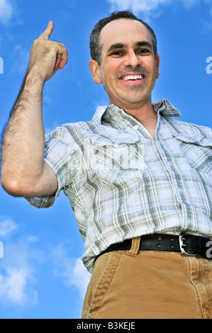 Happy middle aged man gesturing on blue sky background Stock Photo