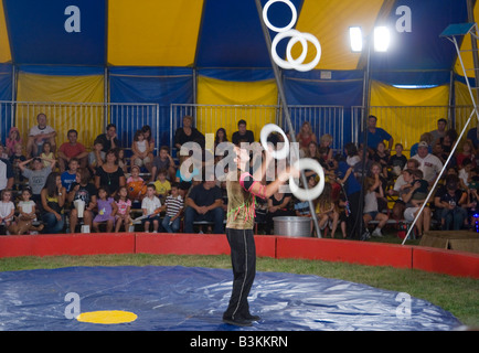 Circus performer juggling rings while audience watches Stock Photo