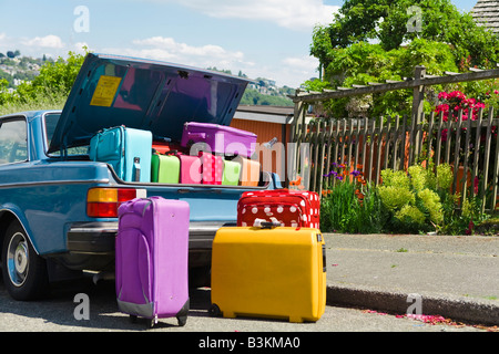 Car trunk loaded with colorful suitcases Stock Photo