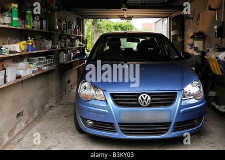 Volkswagen VW Polo car parked in attached house residential property garage shelving for storage of sundry household paraphernalia & tools  England UK Stock Photo