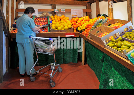 Interior of retail farm shop fruit produce on display woman shopper and trolley Stock Photo
