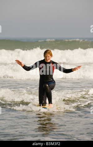 Young lady learning to surf and trying to stand on a surf board. Stock Photo