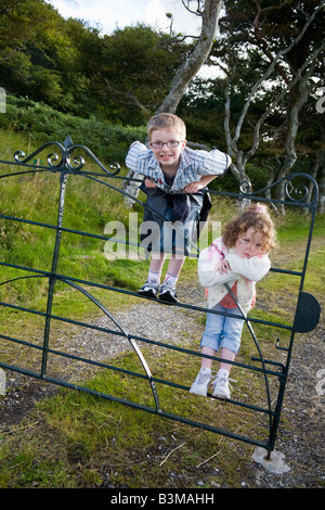 Two Scottish children a boy and a girl play on a gate on the Isle of Skye Scotland Stock Photo