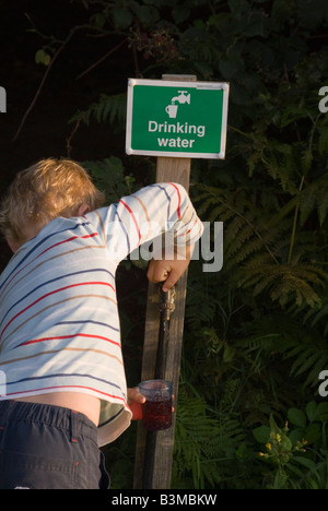 Boy Filling glass with water at uk camping site from outside tap Stock Photo