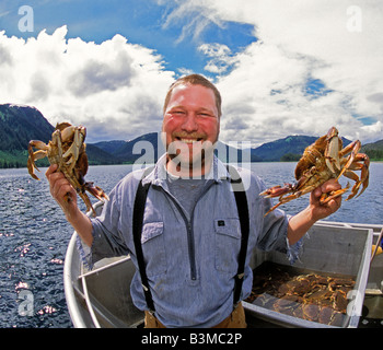 SOUTHEAST ALASKA Happy commercial fisherman holding up freshly caught Dungeness Crab Stock Photo