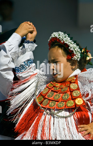 Young girl dancing and singing in the Croatian traditional dress with ducats on the dress and headdress on a folklore festival. Stock Photo