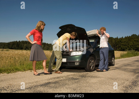 Germany, Bavaria, Three friends with broken down car Stock Photo
