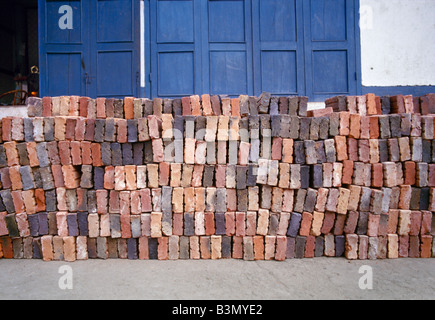 handmade multi coloured bricks in front of a blue wooden door in the former royal capital Luang Prabang in Laos Stock Photo
