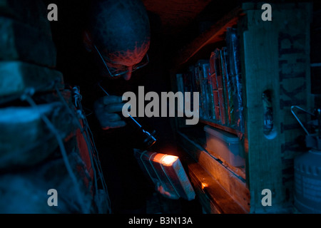 Tattooed hermit Tom Leppard (the Leopard Man) looks through wrapped books in his makeshift underground library, Isle of Skye Stock Photo