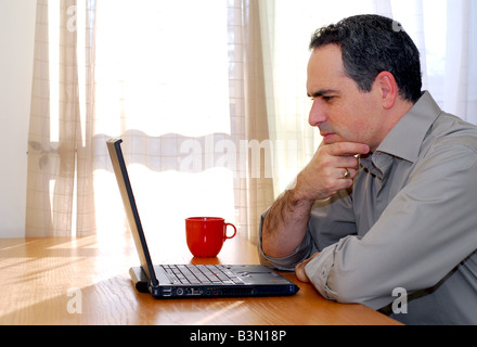 Man sitting at a desk and looking into his computer Stock Photo