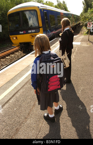Young girls waiting for their train on a railway station platform Travelling to and from school Stock Photo