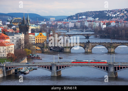 View of Prague down River Vltava in evening, Czech Republic, showing tram crossing bridge Stock Photo