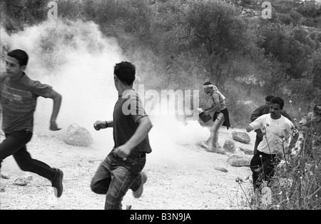 a group of palestinians run away from an israeli attack during a protest against the building of the israeli separation barrier. Stock Photo