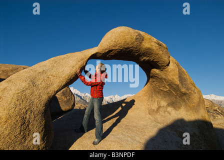 Single woman stands in Mobius Arch at the Alabama Hills with Sierra Nevada Mountains in distance Near Lone Pine California Stock Photo